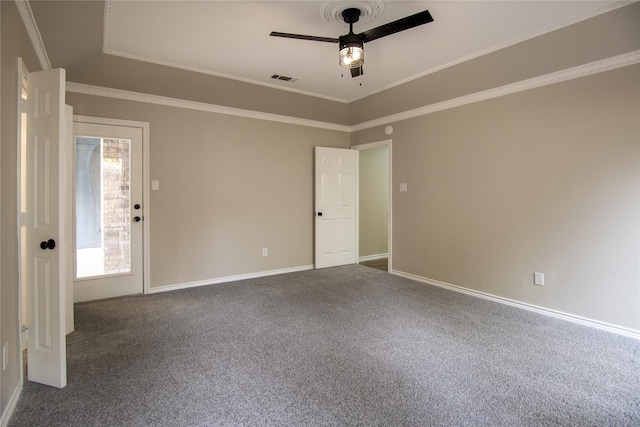 spare room with dark colored carpet, baseboards, visible vents, a ceiling fan, and crown molding