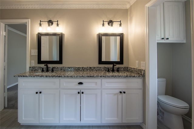 full bath featuring double vanity, toilet, ornamental molding, and a sink