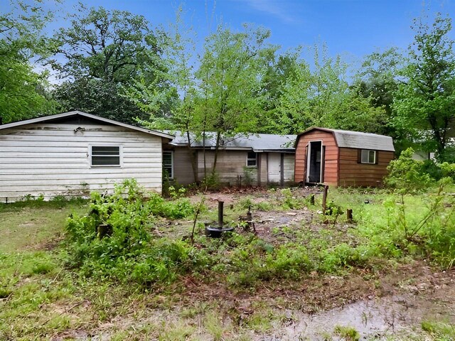 rear view of house featuring an outdoor structure and a shed