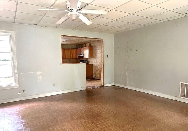 unfurnished living room featuring ceiling fan, baseboards, visible vents, and a paneled ceiling