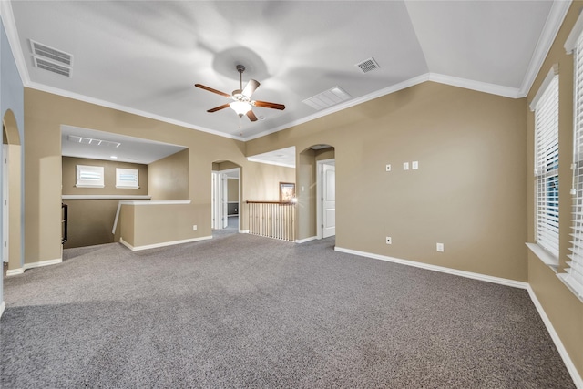 empty room with crown molding, ceiling fan, arched walkways, carpet flooring, and visible vents