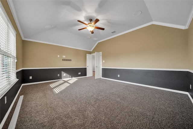 carpeted empty room with lofted ceiling, ornamental molding, visible vents, and ceiling fan