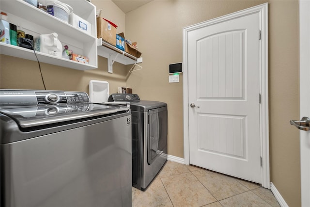 clothes washing area with washer and dryer, baseboards, laundry area, and light tile patterned floors