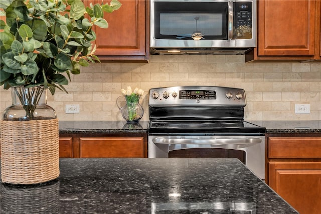 kitchen with dark stone counters, backsplash, and appliances with stainless steel finishes