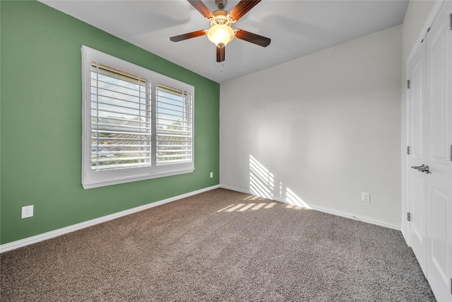 carpeted spare room with ceiling fan and baseboards