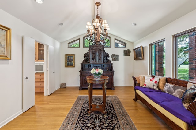 living area with light wood-type flooring, vaulted ceiling, baseboards, and an inviting chandelier