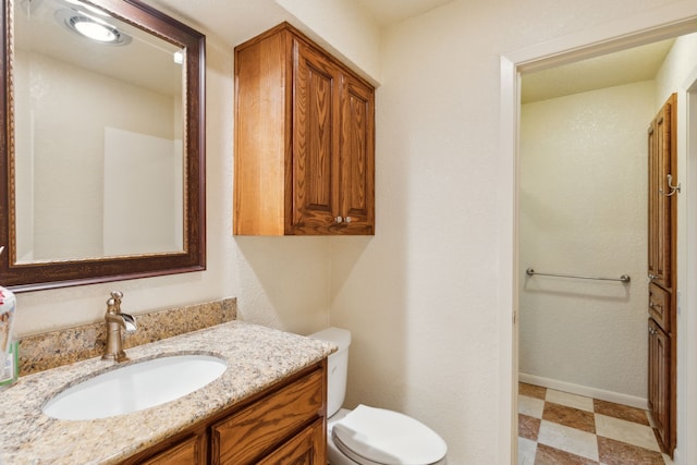 bathroom featuring toilet, vanity, and baseboards