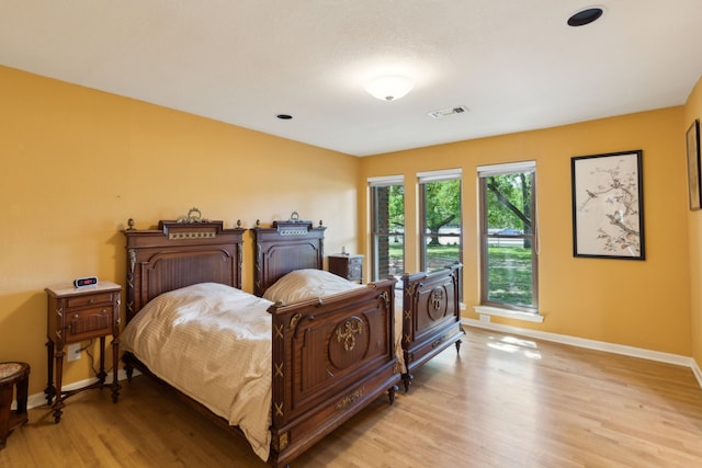 bedroom featuring baseboards, light wood-style floors, and visible vents