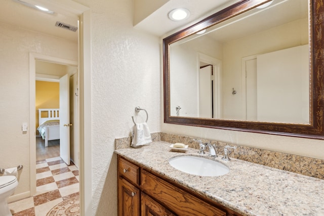bathroom featuring tile patterned floors, toilet, visible vents, a textured wall, and vanity