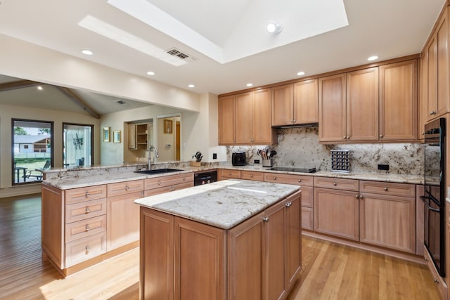 kitchen with a sink, lofted ceiling with beams, black appliances, a peninsula, and light wood-style flooring