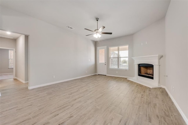 15044 Ted Trl, Aledo, TX 76008 - unfurnished living room with light wood-type flooring, a ceiling fan, a fireplace with raised hearth, and baseboards
