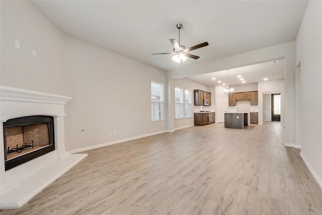 15044 Ted Trl, Aledo, TX 76008 - unfurnished living room featuring a fireplace with raised hearth, a ceiling fan, light wood-type flooring, baseboards, and a chandelier