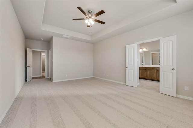 15044 Ted Trl, Aledo, TX 76008 - unfurnished bedroom featuring a tray ceiling, light colored carpet, baseboards, ensuite bathroom, and a ceiling fan