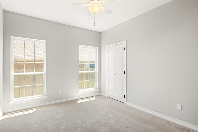 carpeted empty room with ceiling fan and baseboards