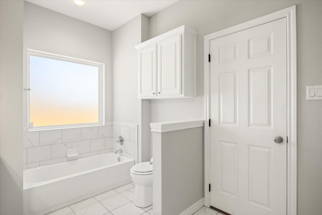 bathroom with marble finish floor, a garden tub, toilet, and baseboards