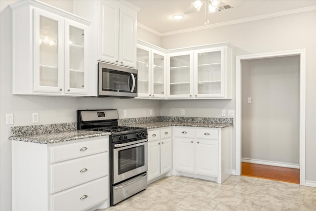 kitchen with white cabinets, ornamental molding, light stone countertops, glass insert cabinets, and appliances with stainless steel finishes