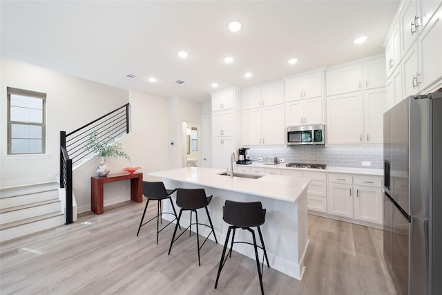 7112 Amber Grove Ct, Dallas, TX 75231 - kitchen with a breakfast bar, a sink, stainless steel appliances, tasteful backsplash, and light wood-type flooring