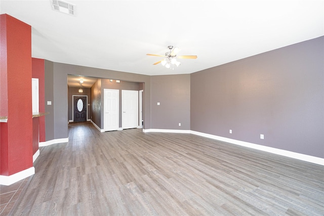 unfurnished living room with baseboards, a ceiling fan, wood finished floors, and visible vents