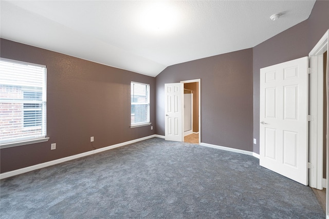 unfurnished bedroom featuring vaulted ceiling, baseboards, and carpet