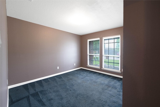 unfurnished room with dark carpet and baseboards