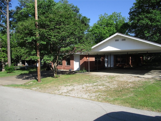 view of front of property with a front lawn, brick siding, driveway, and an attached carport