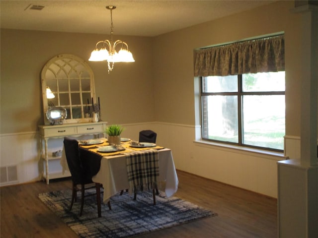 dining space with a wainscoted wall, a chandelier, wood finished floors, and visible vents