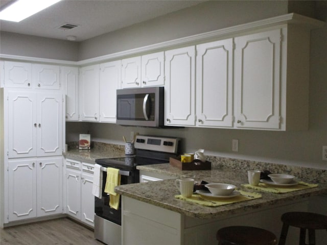 kitchen with white cabinets, stainless steel appliances, and a peninsula