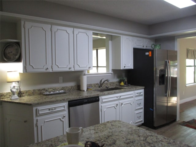 kitchen with open shelves, wood finished floors, a sink, stainless steel appliances, and white cabinetry