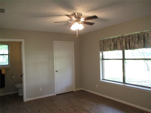 unfurnished bedroom featuring wood finished floors, baseboards, and multiple windows
