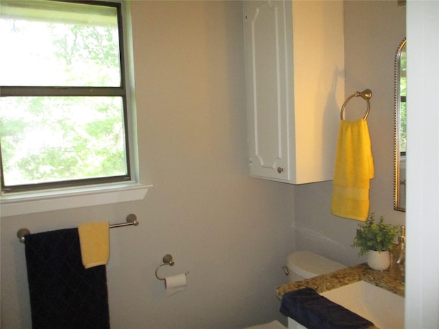 bathroom with toilet, vanity, and plenty of natural light