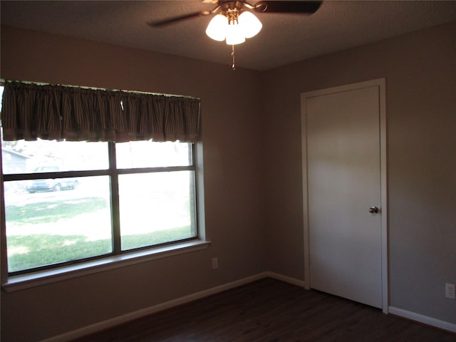 unfurnished room with dark wood finished floors, baseboards, and ceiling fan