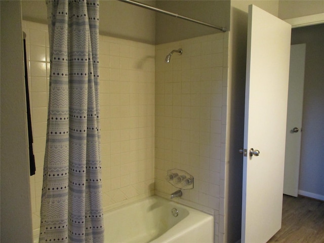 full bathroom featuring baseboards, wood finished floors, and shower / tub combo with curtain