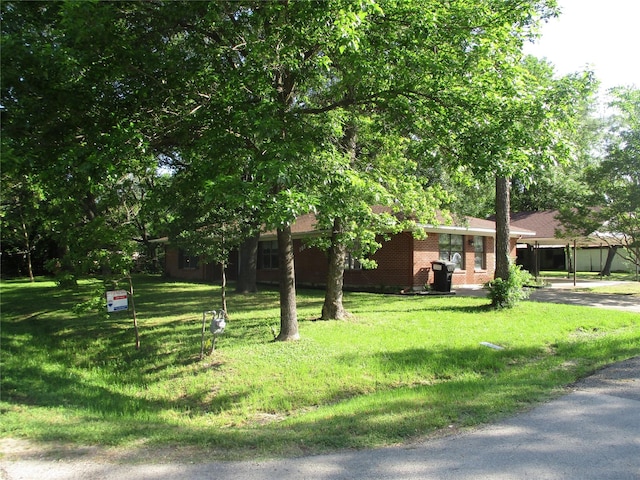 view of front of house featuring brick siding, a front yard, and a carport