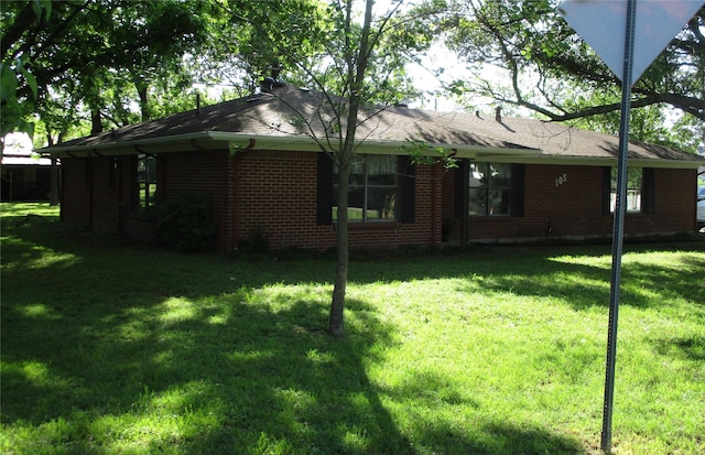 rear view of house featuring brick siding and a yard