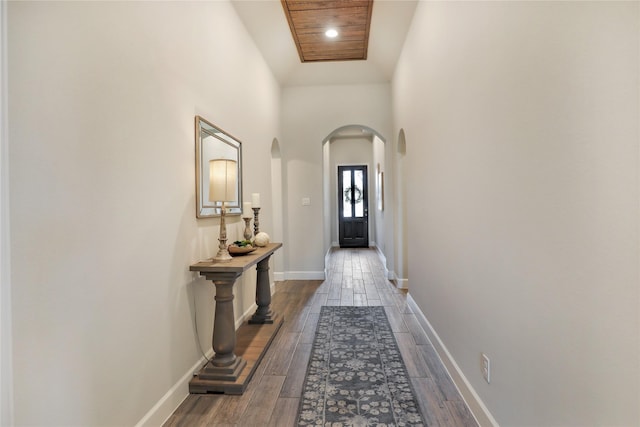 doorway with baseboards, arched walkways, dark wood-style flooring, recessed lighting, and a high ceiling