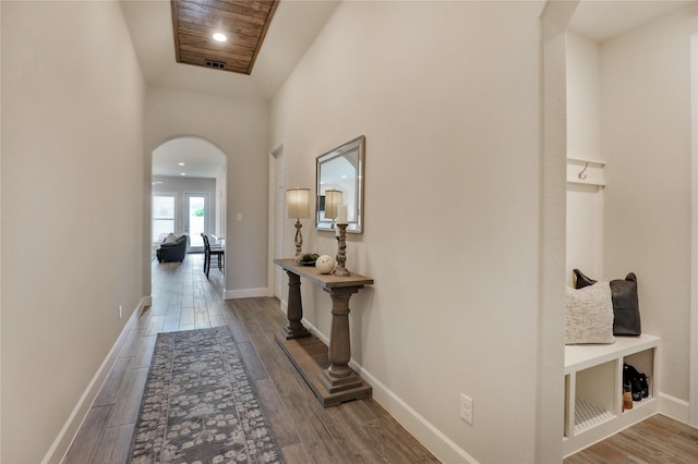 hallway featuring recessed lighting, arched walkways, wood finished floors, and baseboards