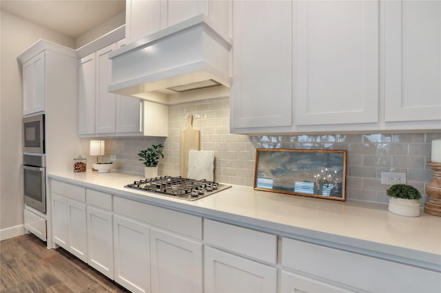 kitchen featuring white cabinetry, stainless steel gas cooktop, wall chimney exhaust hood, and light countertops