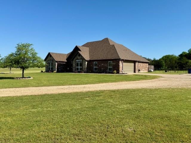view of front of property featuring brick siding, an attached garage, driveway, and a front yard