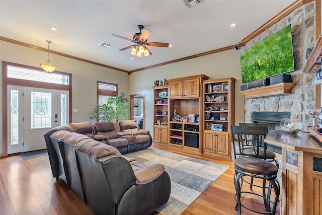 living room featuring a fireplace, light wood-type flooring, visible vents, and a ceiling fan