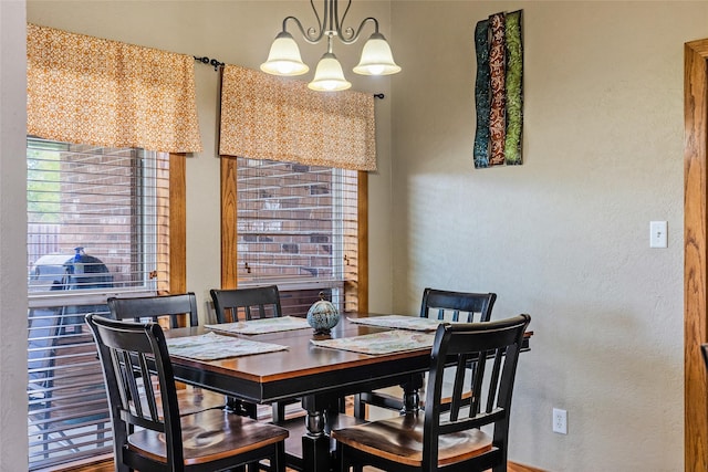 dining space with a textured wall and a notable chandelier