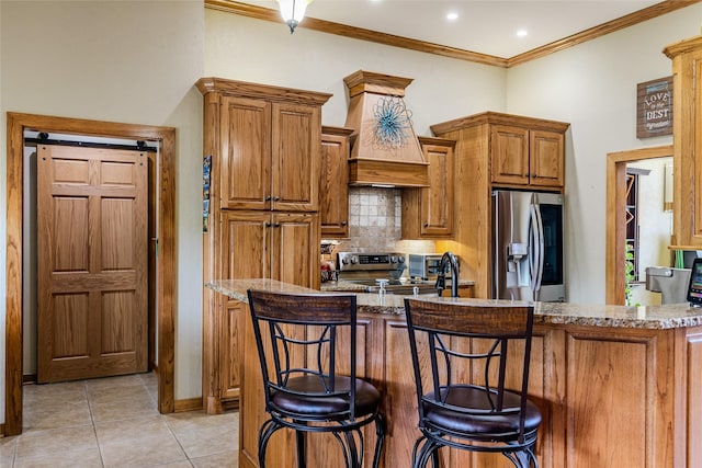 kitchen with decorative backsplash, appliances with stainless steel finishes, custom range hood, brown cabinetry, and ornamental molding
