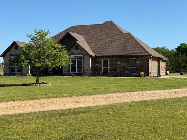 back of house featuring a lawn, brick siding, and a garage