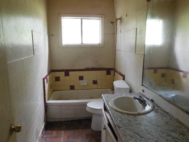 full bath with tile walls, toilet, vanity, and a wainscoted wall