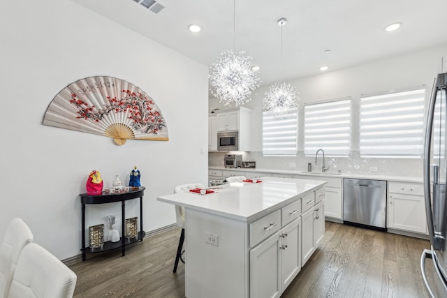 kitchen with wood finished floors, stainless steel appliances, visible vents, and a sink
