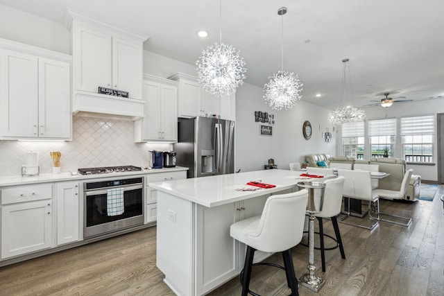 kitchen featuring a center island, tasteful backsplash, open floor plan, stainless steel appliances, and white cabinetry
