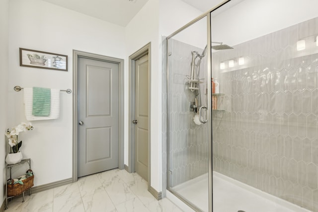 full bath featuring baseboards, marble finish floor, and a stall shower