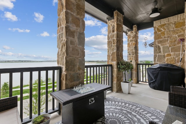 balcony featuring grilling area, a water view, and a ceiling fan