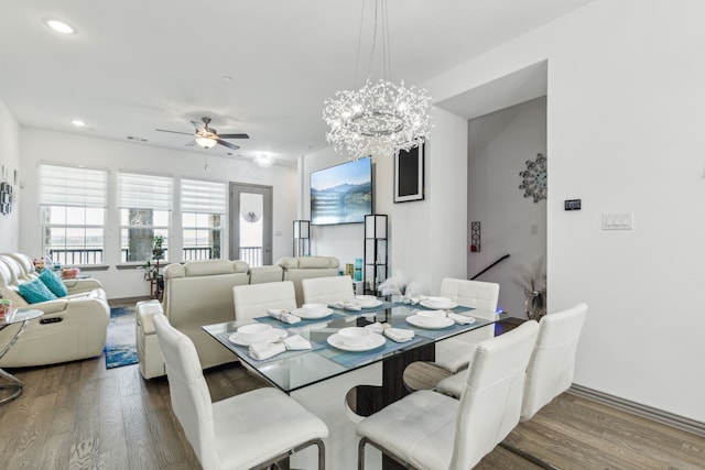 dining space with ceiling fan with notable chandelier, baseboards, wood finished floors, and recessed lighting
