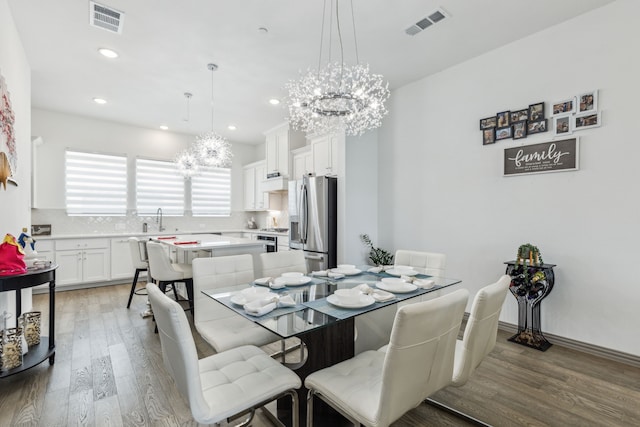 dining room with light wood-style floors, visible vents, and a notable chandelier