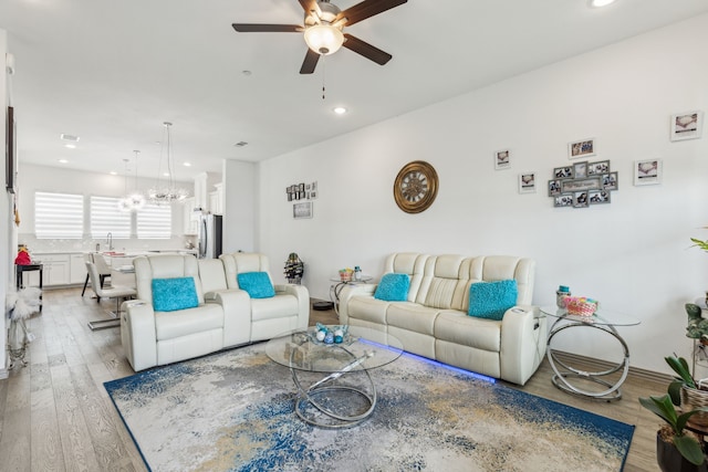 living room with recessed lighting, light wood-style floors, and ceiling fan with notable chandelier